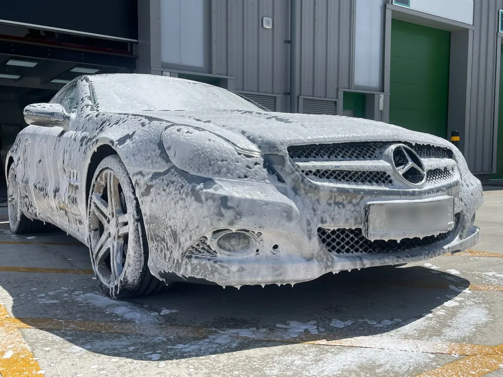 Car covered in snow foam before going through detailing service.